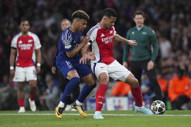 William Saliba berduel dengan Desire Doue dalam laga Arsenal vs PSG di leg pertama semifinal Liga Champions 2024/2025, Rabu (30/4/2025) dini hari WIB. (c) AP Photo/Kirsty Wigglesworth